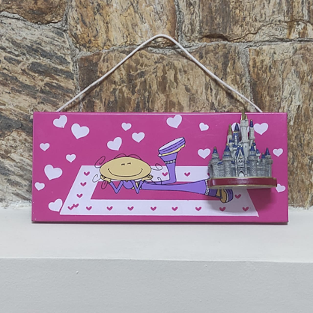 Placa magnética rosa da empresa Giroart com o design de uma menina deitada em um tapete.